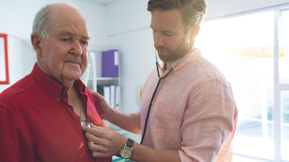 A GP examines a patient, both are standing.
